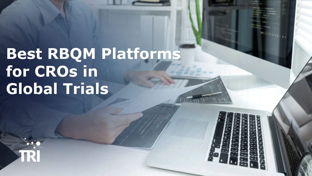 Professional working at a desk reviewing clinical trial documents on a computer, representing RBQM software platforms for CROs managing global clinical trials.